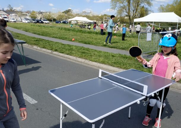 Deux enfants jouent au tennis de table en extérieur